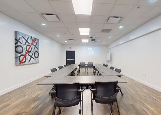 Sala de conferencias con 3 mesas largas con manteles blancos y sillas plegables negras