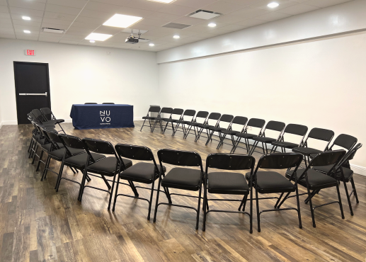 Sala de conferencias con 3 mesas largas con manteles blancos y sillas plegables negras
