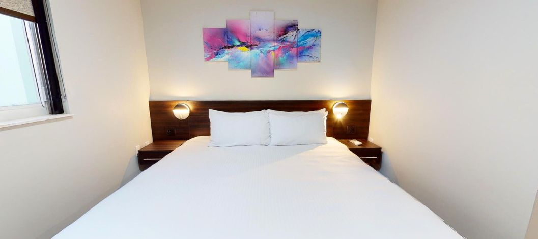 Cama King con dos mesitas de noche junto a una ventana