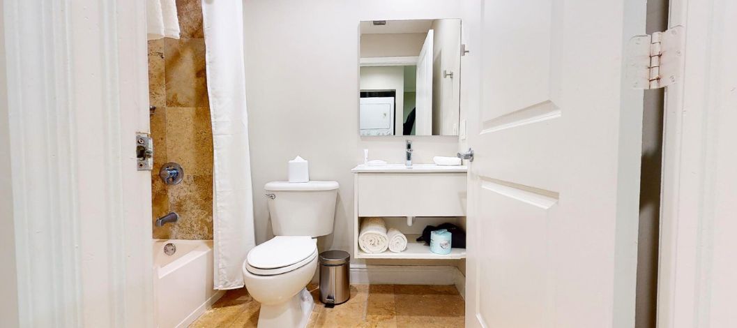 Zona de estar con sofá, otomana, escritorio y televisor de pantalla plana